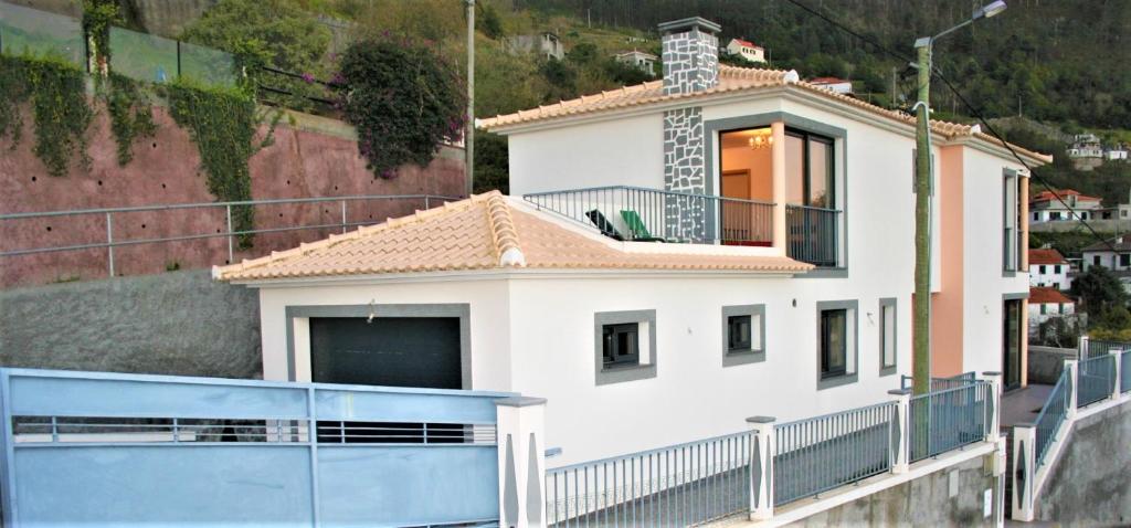 ein weißes Haus mit einem Balkon und einem Zaun in der Unterkunft The Rose House in Arco da Calheta