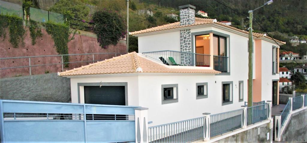 Casa blanca con balcón y valla en The Rose House, en Arco da Calheta