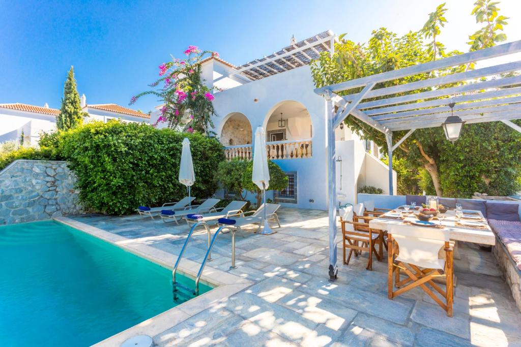 une villa avec une piscine, une table et des chaises dans l'établissement Villa Scirocco, à Spetses