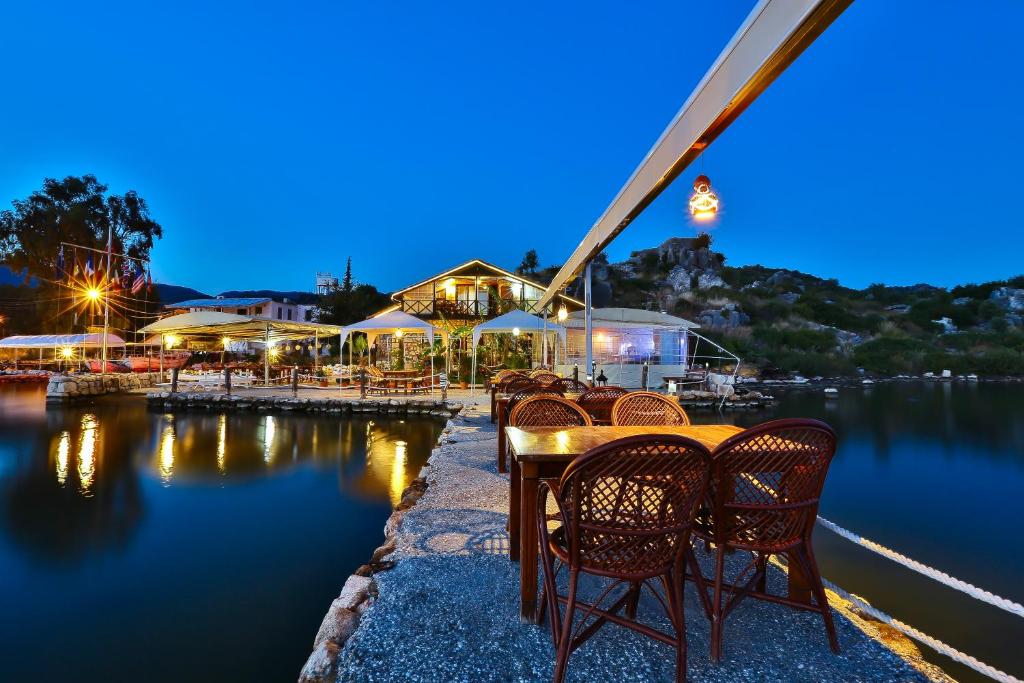 a table and chairs next to a lake at night at Kekova Theimussa in Kaleucagız