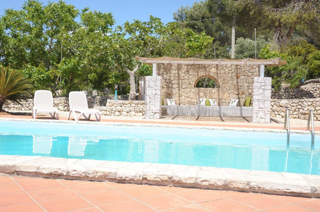 una piscina con 2 sillas y un cenador en Contrada Borgin en Marina di Pescoluse