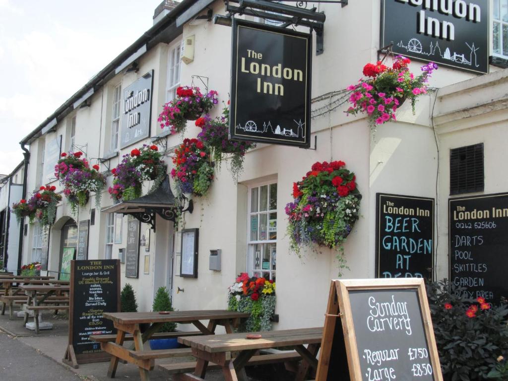 a building with tables and flowers in front of it at The London Inn in Cheltenham