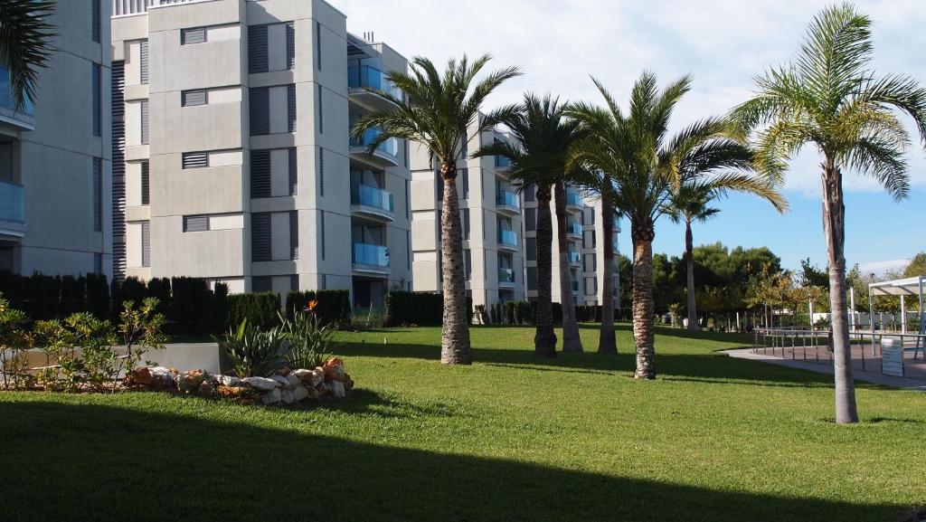 un parque con palmeras frente a un edificio en Apartamentos Verger de Denia, en Els Poblets