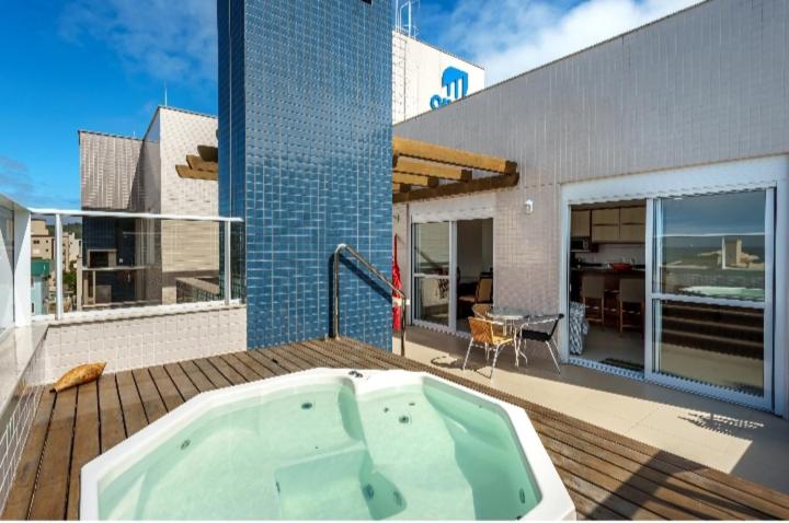 a hot tub sitting on a deck next to a building at Cobertura com Jacuzzi privativa in Governador Celso Ramos