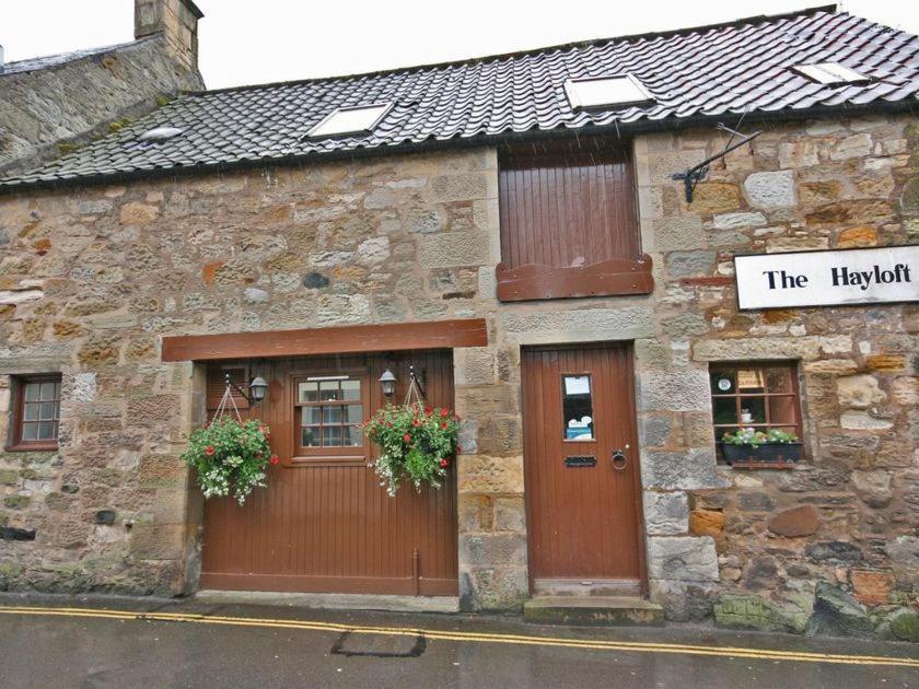 a stone building with two doors and a sign on it at The Hayloft in Falkland
