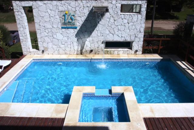 una gran piscina azul con una pared de piedra en Duplex Valeria Soho en Valeria del Mar