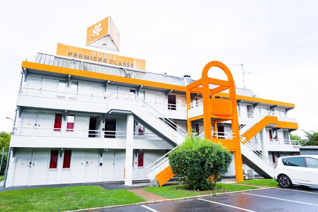 a hotel with a large orange building with a parking lot at Premiere Classe St Quentin in Saint-Quentin