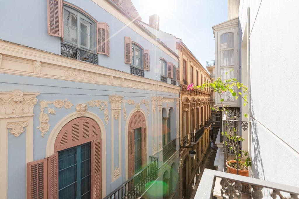 un callejón en un edificio antiguo con balcones y flores en Corazón de Málaga, en Málaga