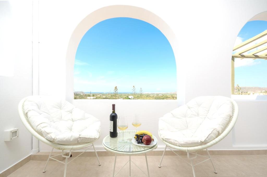 a room with two white chairs and a table with a bottle of wine at Spacious Villa in Naxos with Sea View in Naxos Chora