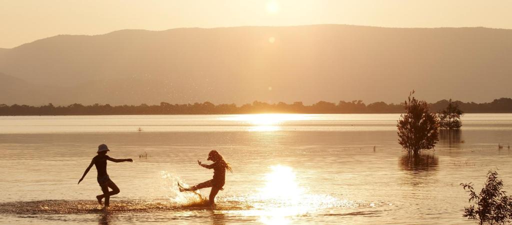zwei Menschen, die bei Sonnenuntergang im Wasser laufen in der Unterkunft Lake Fyans Holiday Park in Lake Fyans