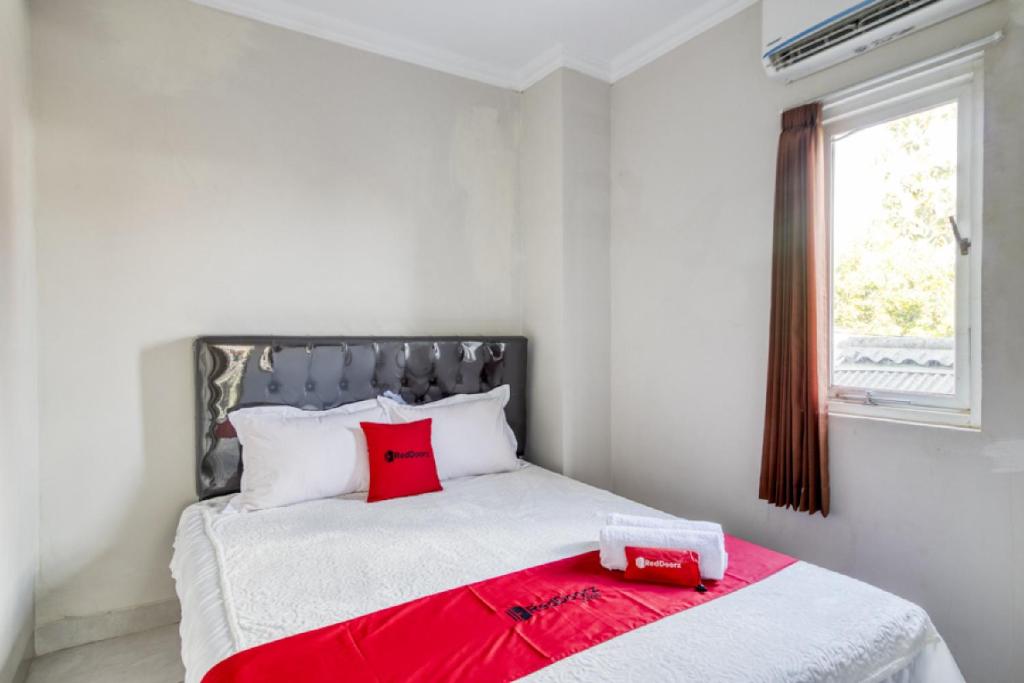 a bedroom with a bed with a red blanket on it at RedDoorz near Condongcatur Bus Station in Yogyakarta