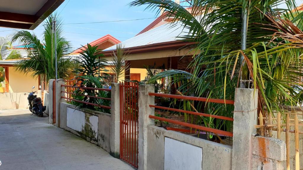 einen Zaun vor einem Haus mit Palmen in der Unterkunft Indino Guesthouse in Moalboal
