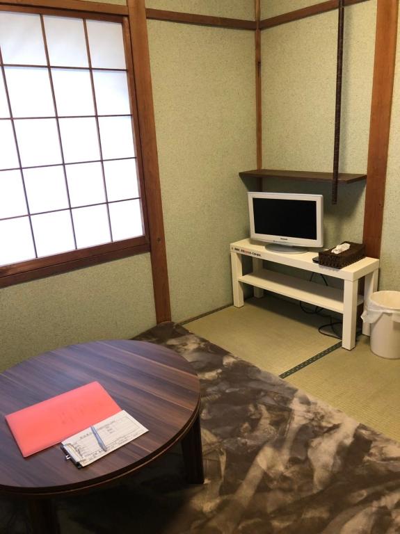 a living room with a table and a tv at Oyado Zen in Kusatsu