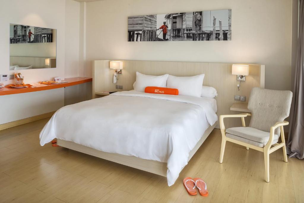a bedroom with a large white bed and a chair at HARRIS Resort Barelang Batam in Sagulung