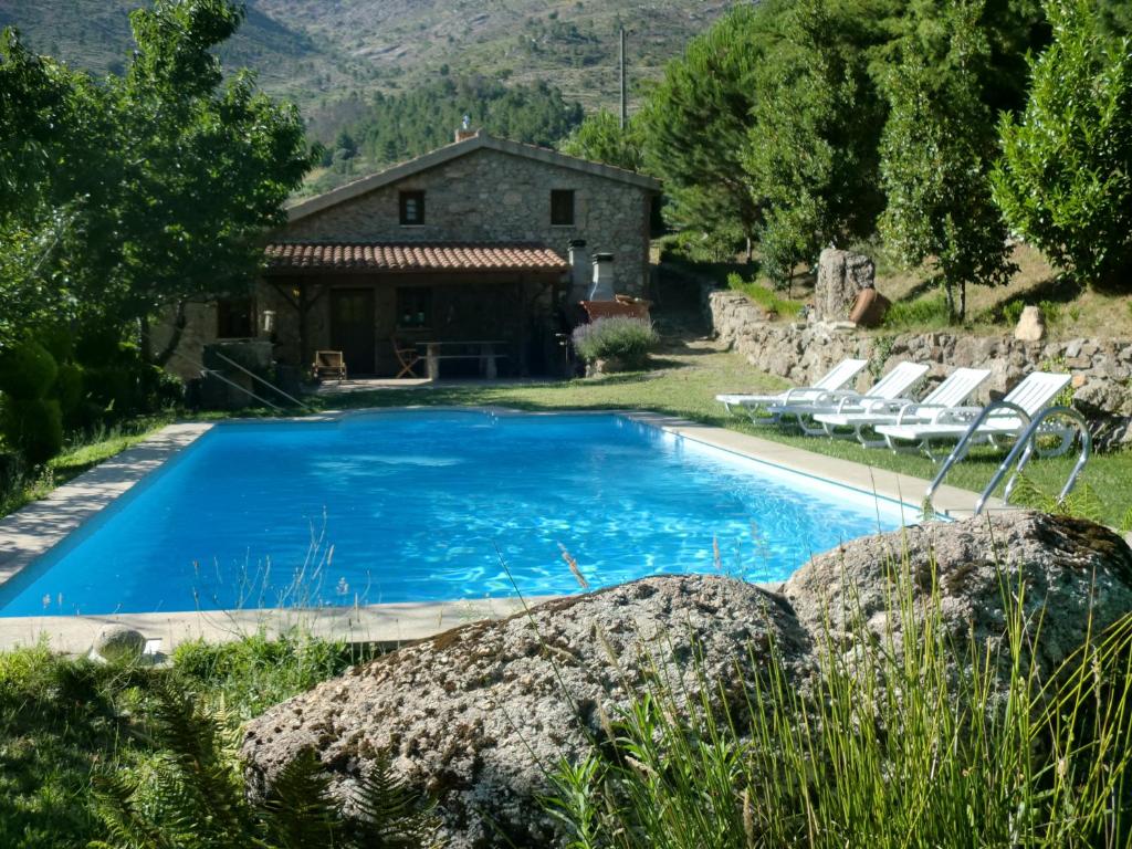 una piscina frente a una casa con sillas alrededor en Quinta Do Circo - Serra Da Estrela - Turismo Rural, en Cortes do Meio