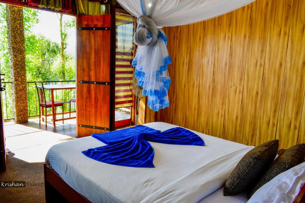 Schlafzimmer mit einem Bett mit blauer Bettwäsche und einem Fenster in der Unterkunft Will Guest Homestay in Ella