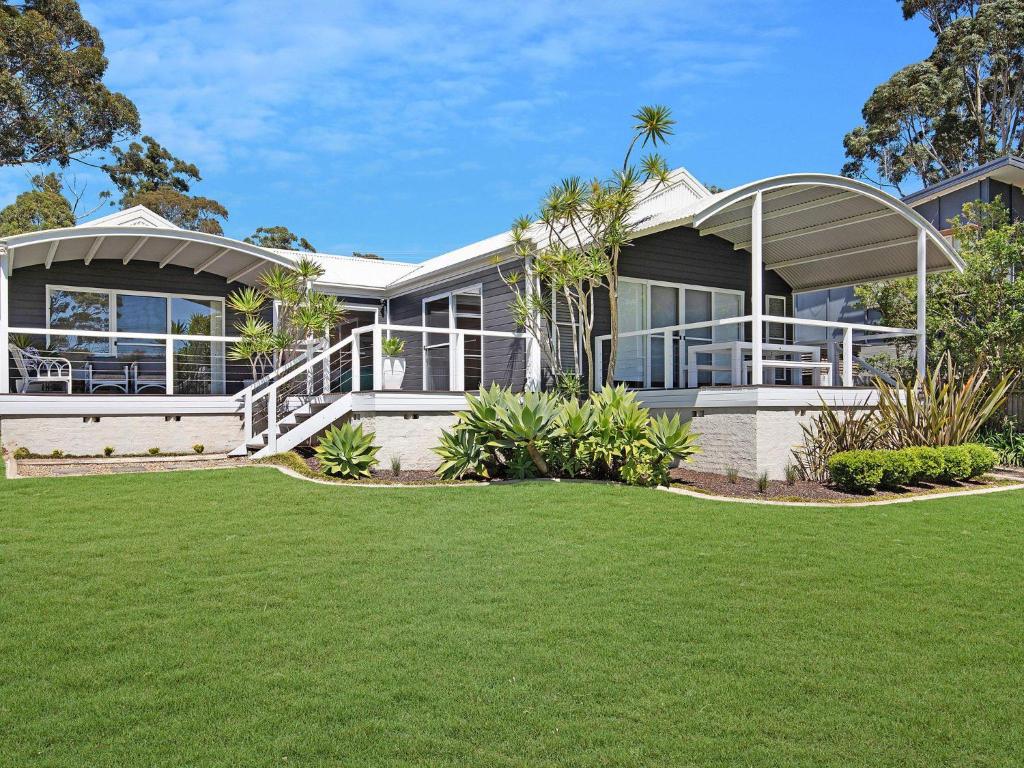 a house with a lawn in front of it at Akarana Beach House by Jervis Bay Rentals in Vincentia