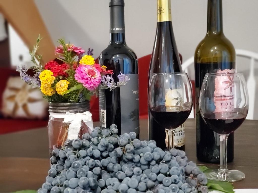 a table with two bottles of wine and a bowl of grapes at A Cozy Loft in Templeton in Templeton