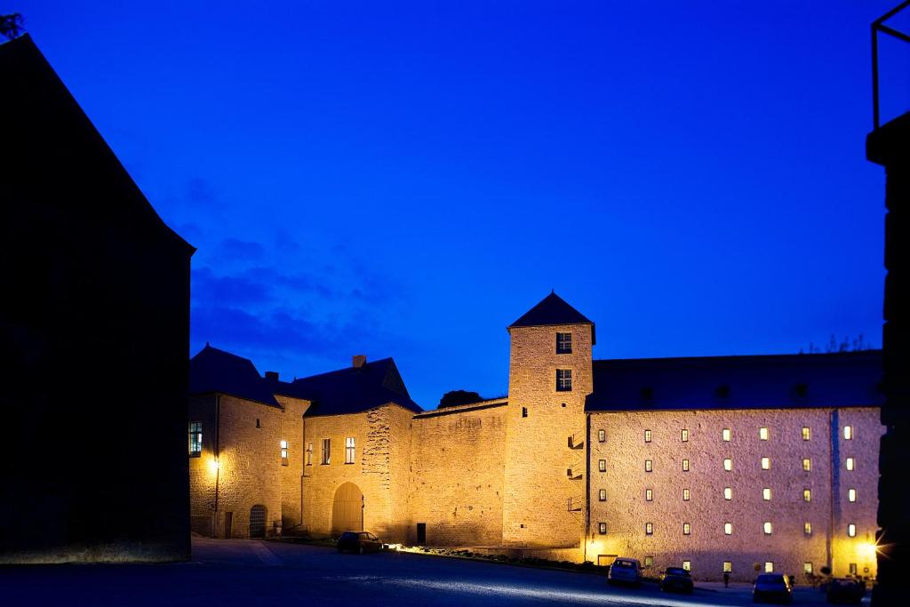 un grand château éclairé la nuit dans l'établissement Hôtel Le Château Fort de Sedan, à Sedan