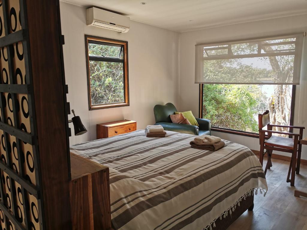 a bedroom with a bed and a chair and a window at Mama Out of Africa in Livingstone