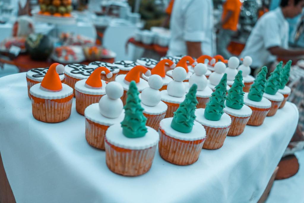 a table topped with cupcakes with orange and green icing at HARRIS Resort Barelang Batam in Sagulung