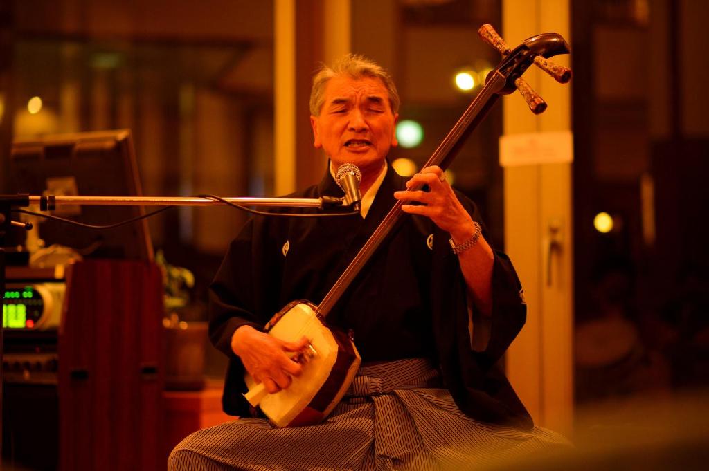 Un homme joue de la guitare dans une pièce dans l'établissement Hotel Grand Mer Sankaiso, à Ajigasawa