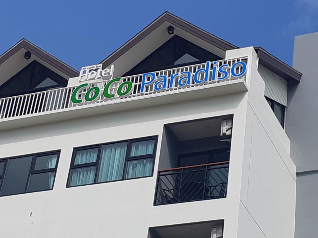 Un bâtiment blanc avec un panneau en haut dans l'établissement Coco Paradiso Phuket SHA, à Phuket