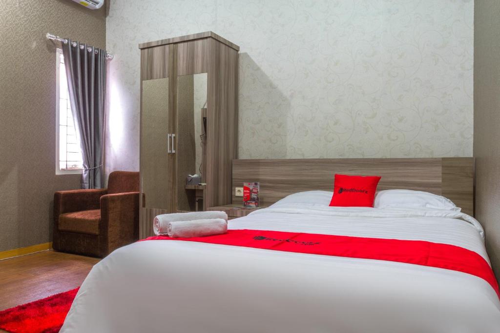 a bedroom with a large white bed with a red pillow at RedDoorz Plus near IPDN in Sumedang