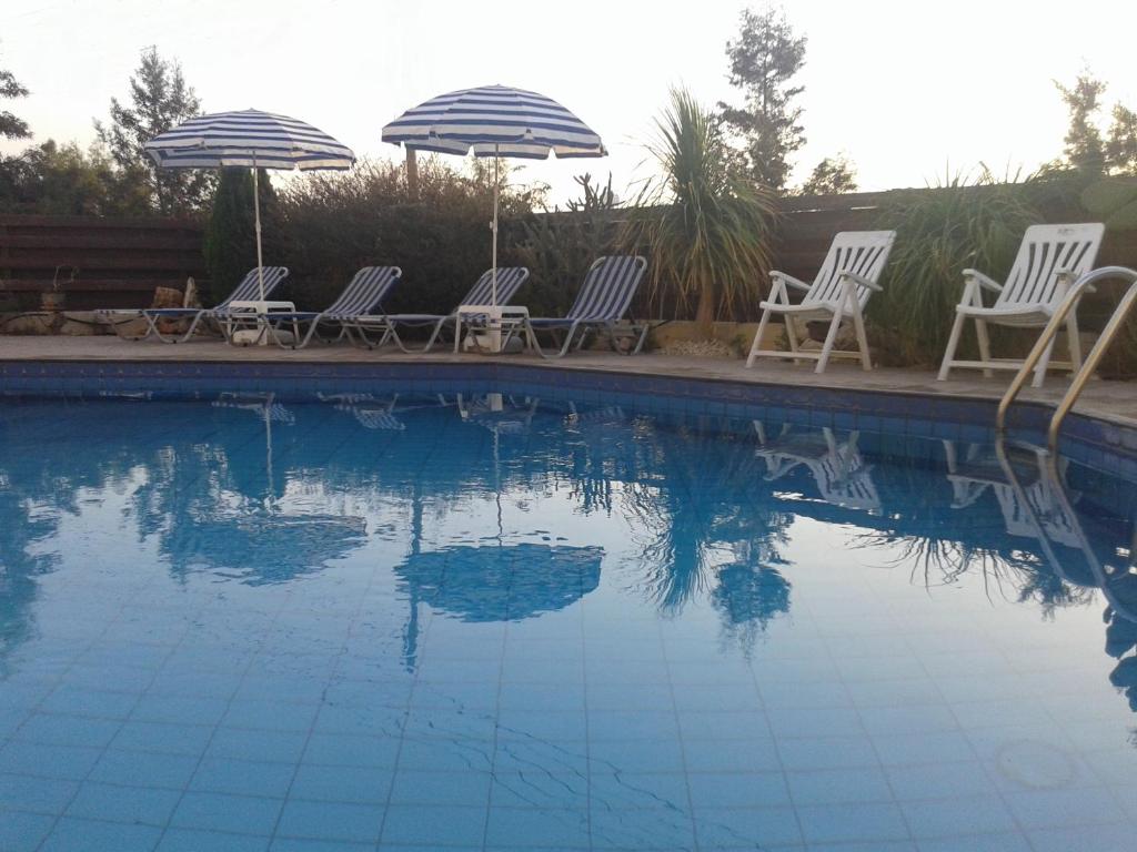 un gruppo di sedie e ombrelloni seduti accanto alla piscina di Arilena Holiday Apartments a Paphos