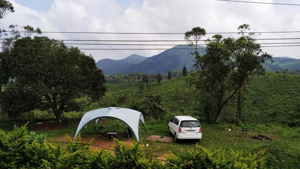 a white car parked in a field with a tent at Whispering Pinewoods in Pīrmed