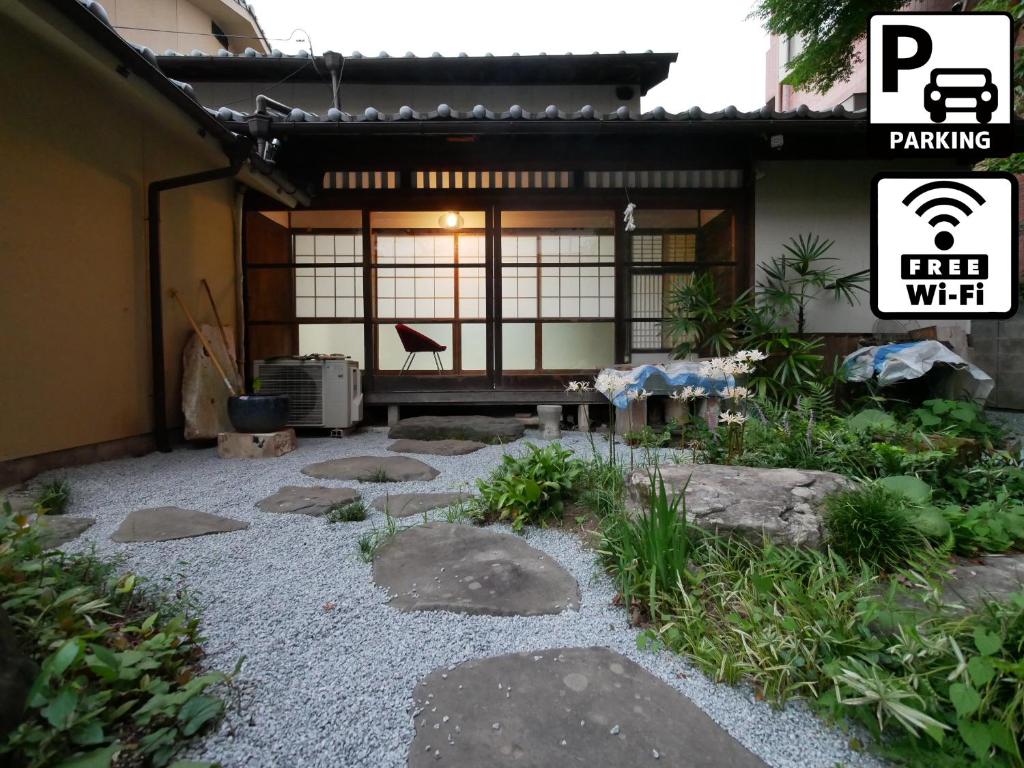 an asian garden with rocks and a building at SUMITSUGU HOUSE Grandpa in Kumamoto