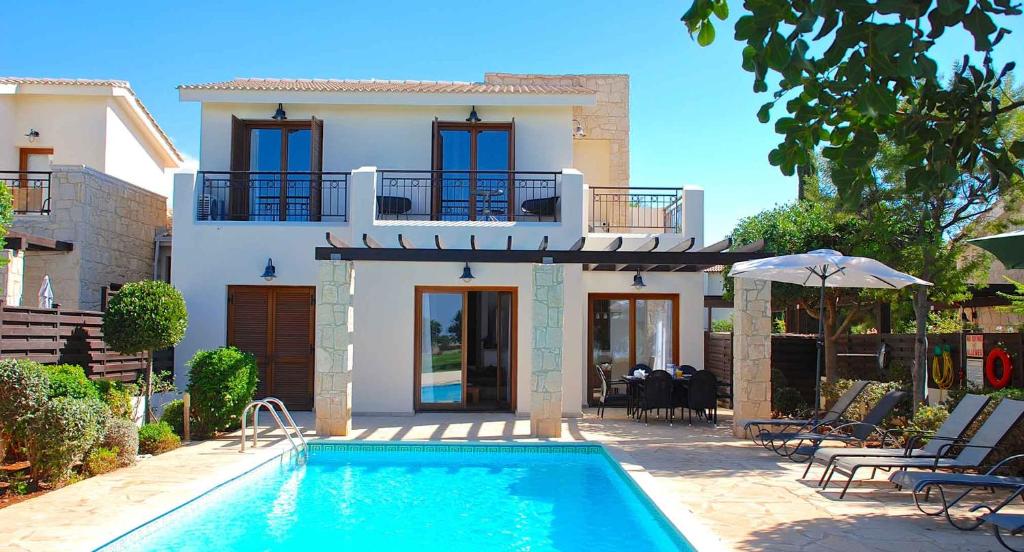 a villa with a swimming pool in front of a house at 3 bedroom Villa Cardia with private pool, Aphrodite Hills Resort in Kouklia