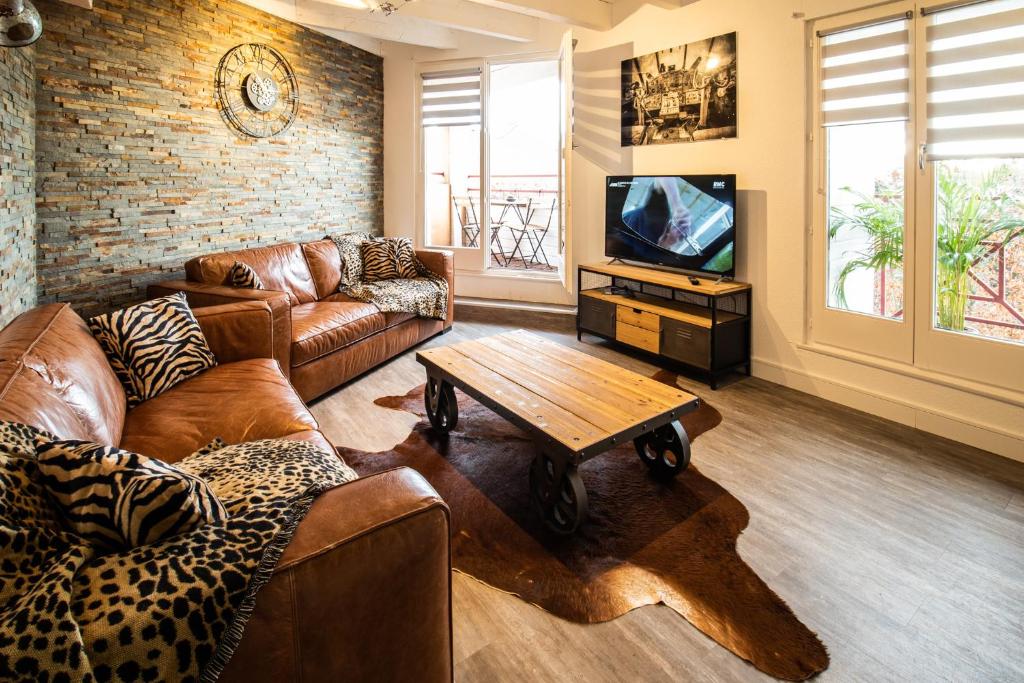 a living room with leather couches and a tv at Le rohan sawadee in Colmar