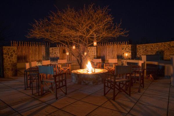 uma fogueira com cadeiras e uma mesa com uma árvore em Ntamba Safari Lodge em Matlhagame