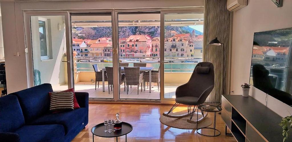 ein Wohnzimmer mit einem blauen Sofa und einem Balkon in der Unterkunft Mitra Zonata Pink in Omiš