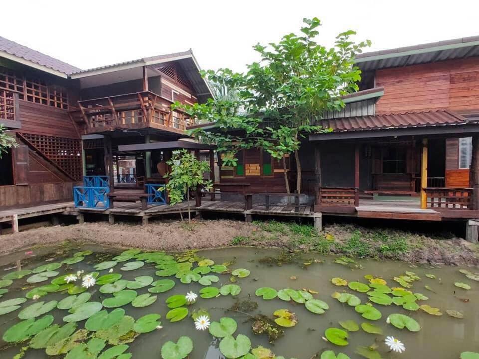 a house with a pond of water lilies at BAANYA HOMESTAY Ko Kret in Nonthaburi