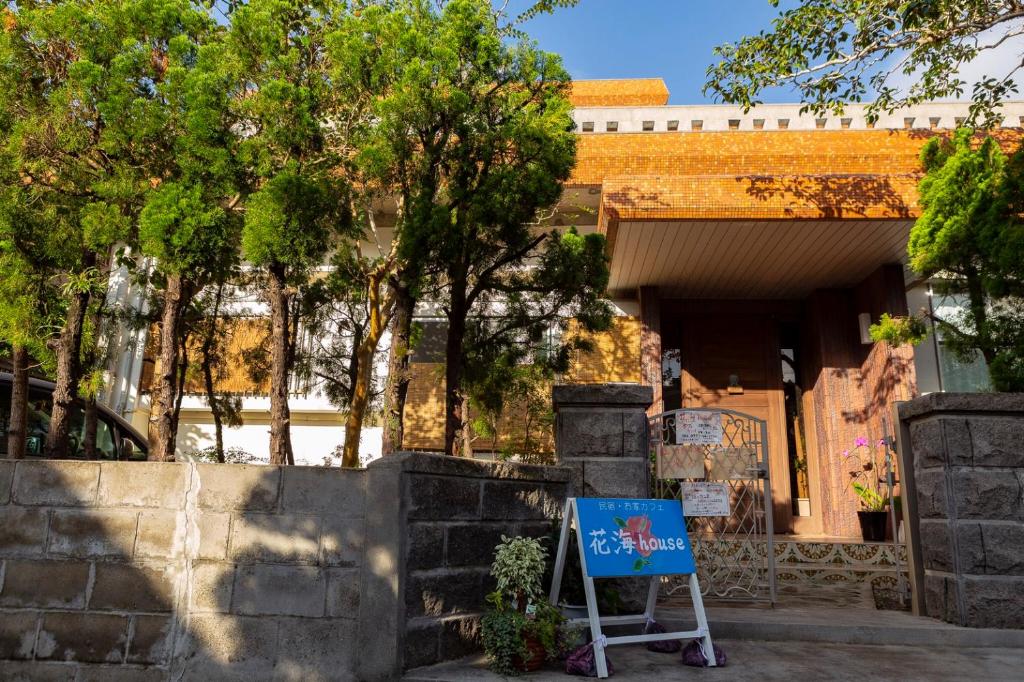 un cartello di fronte a un edificio alberato di Kami House ad Amami