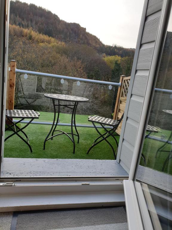 een patio met een tafel en stoelen op een balkon bij Riverside cottage in Treherbert