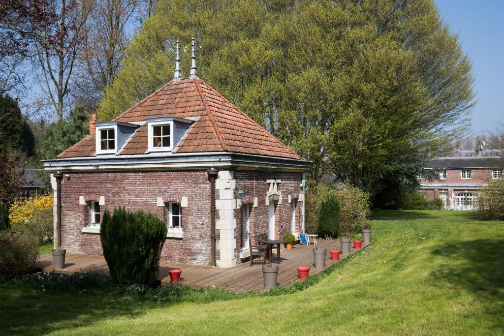 ein altes Backsteingebäude mit einem Dach auf einem Feld in der Unterkunft LA MAISON DES CHEVAUX in Eu