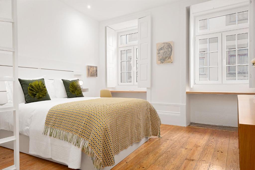 a white bedroom with a bed and two windows at Oporto Classic Apartment in Porto