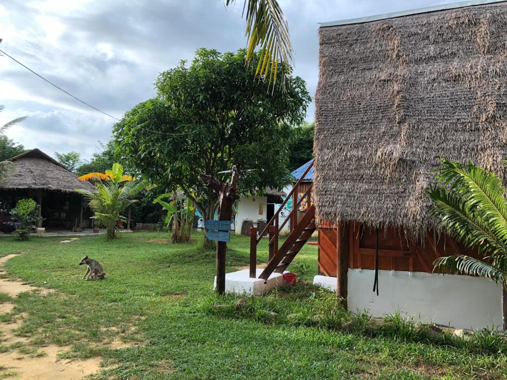 a dog sitting next to a house with a thatch roof at Lazy Bones in Koh Rong Sanloem