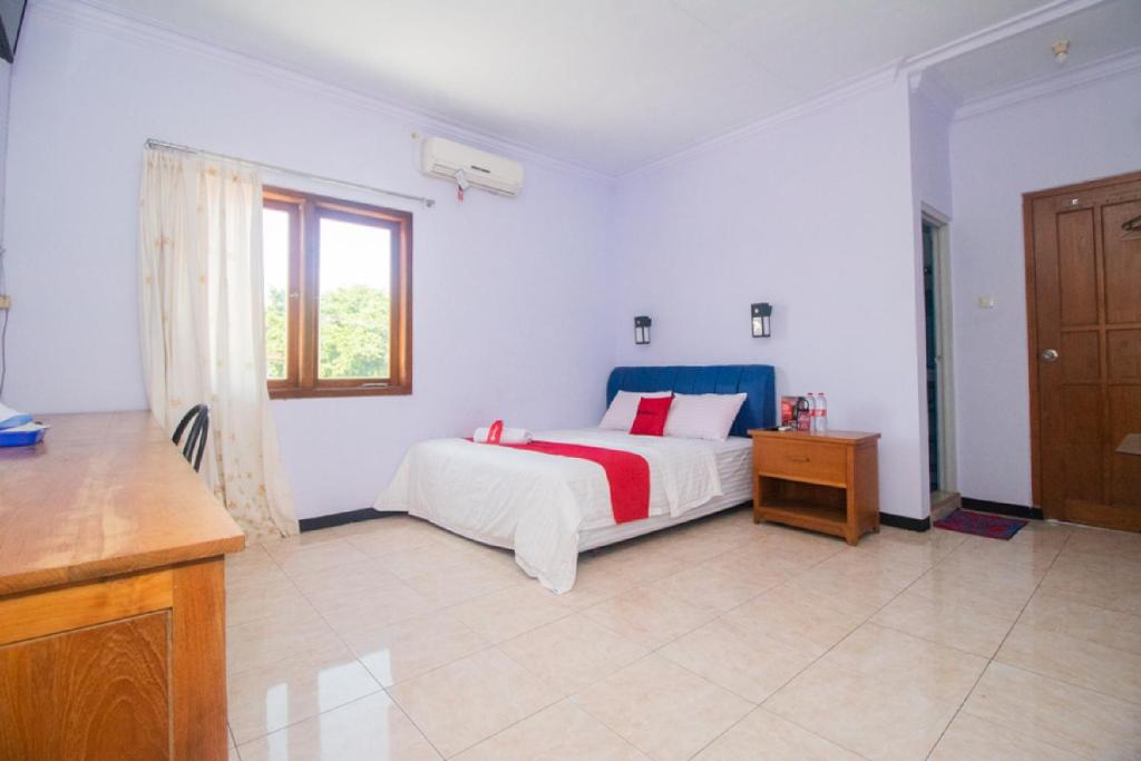 a white bedroom with a bed and a window at RedDoorz near Pantai Boom in Banyuwangi
