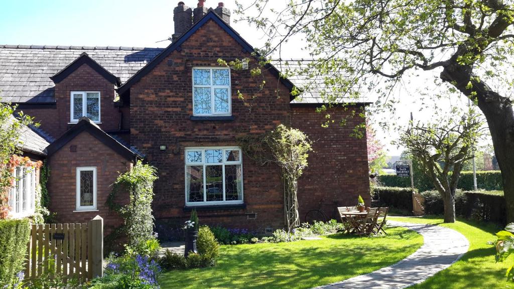 uma casa de tijolos castanhos com um jardim de relva em The School House em Warrington