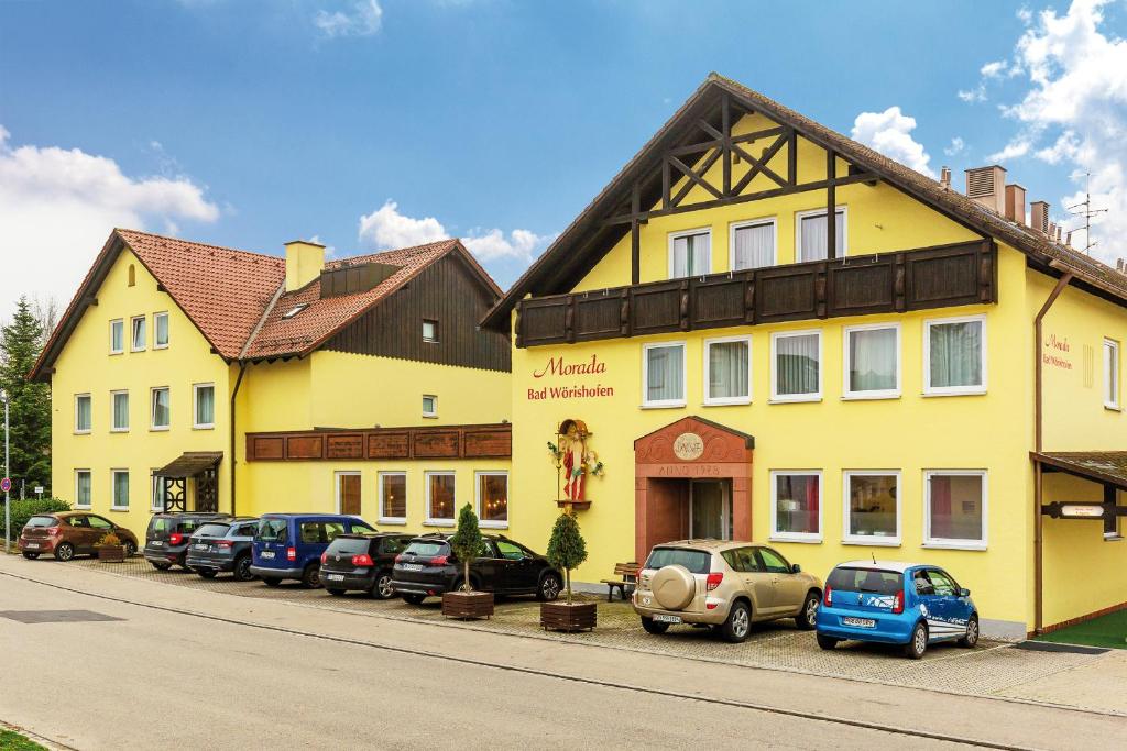 a row of cars parked in front of a yellow building at Morada Hotel Bad Wörishofen in Bad Wörishofen