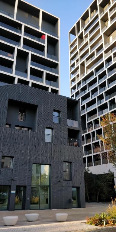 un bâtiment noir avec deux grands bâtiments en arrière-plan dans l'établissement @Coloc Gîtes urbains, à Nantes