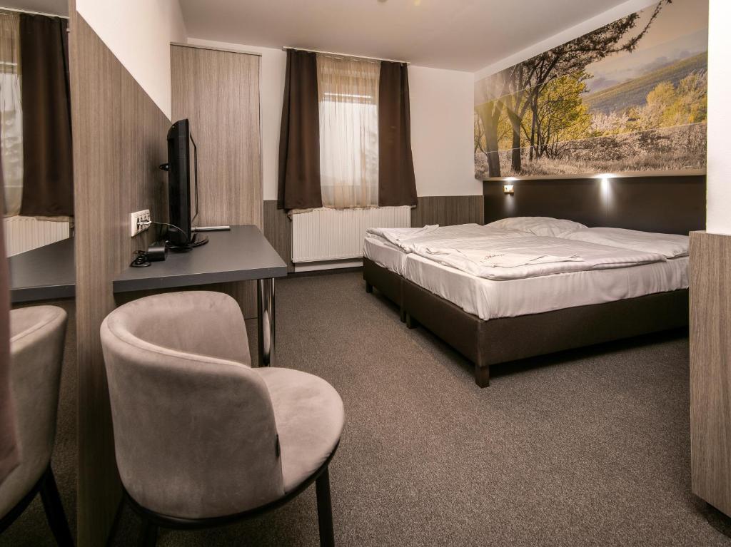 Dormitorio con cama, escritorio y TV en Andante Pension & Restaurant en Szentgotthárd