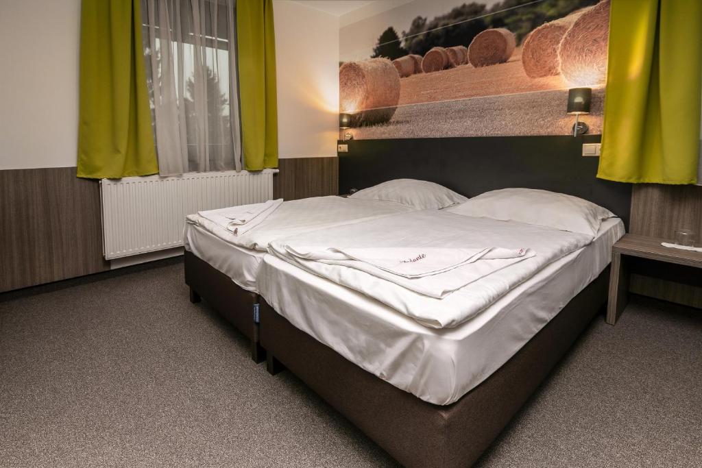 duże łóżko w pokoju z żółtymi zasłonami w obiekcie Andante Pension & Restaurant w mieście Szentgotthárd
