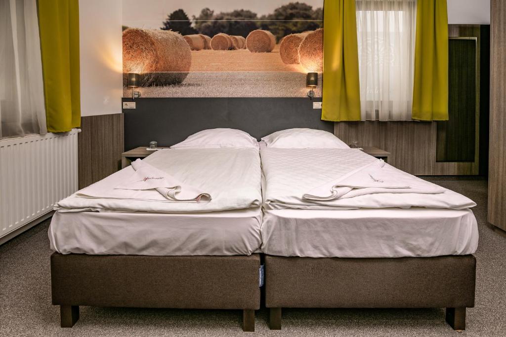 łóżko z białą pościelą i poduszkami w pokoju w obiekcie Andante Pension & Restaurant w mieście Szentgotthárd