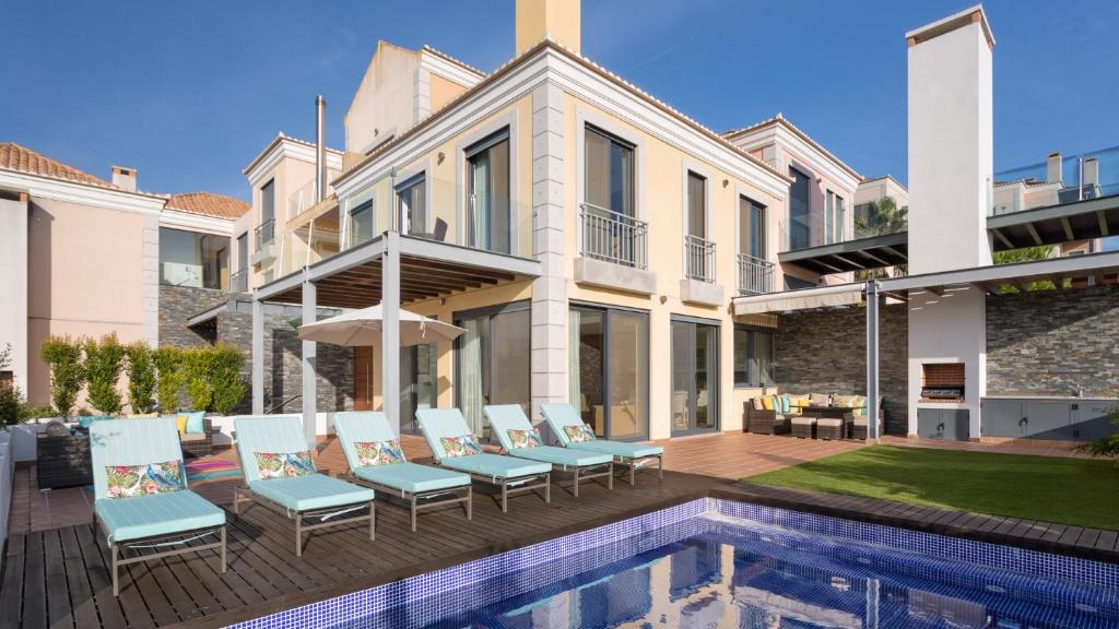 uma casa com uma piscina com cadeiras e uma casa em Caprice em Almancil