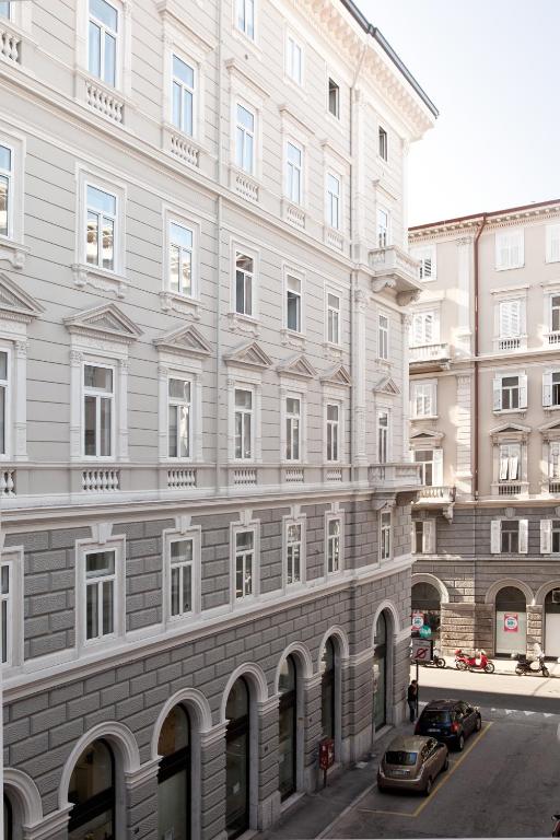 a large white building with cars parked in front of it at Palazzo Talenti 1907 in Trieste